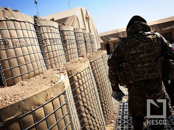 Solider walking within a FOB built using HESO barriers