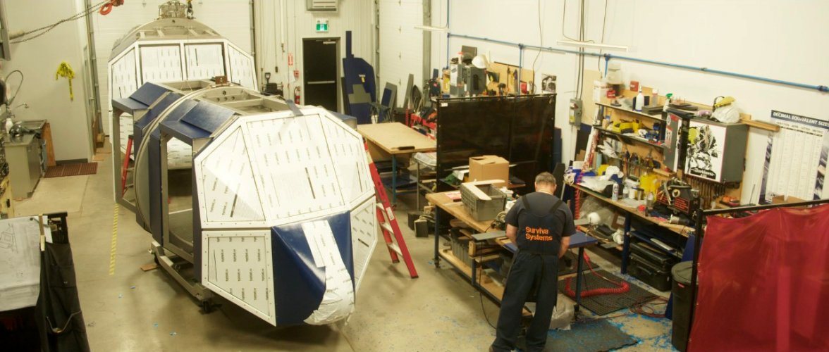 A craftsman in the SSL assembly shop fits the outer skins to the basic frame of a METS® Model 5 (front) and a METS® Model 40 (rear).