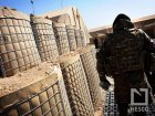 Solider walking within a FOB built using HESO barriers