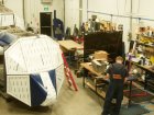 A craftsman in the SSL assembly shop fits the outer skins to the basic frame of a METS® Model 5 (front) and a METS® Model 40 (rear).